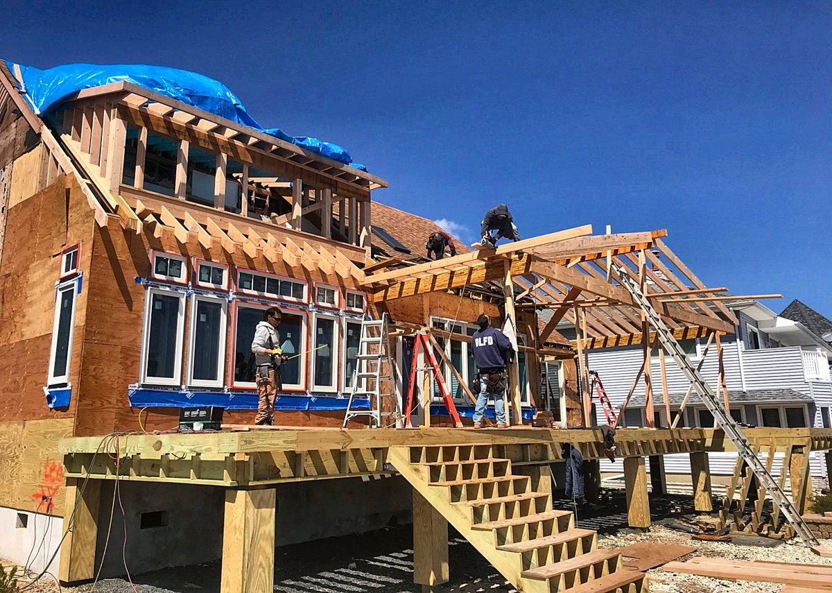 Crew framing a new dormer and porch roof on a waterfront house